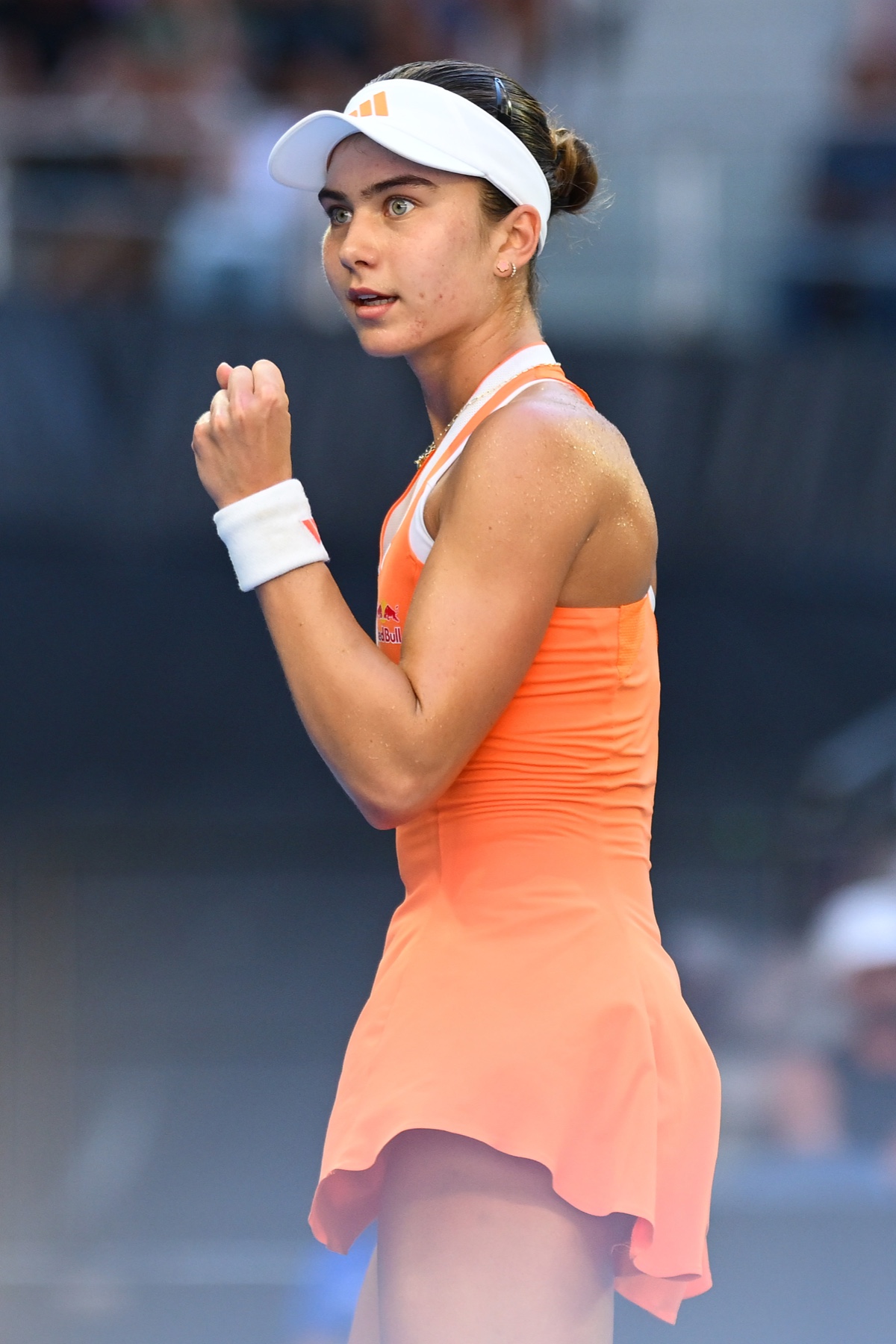 Iva Jovic celebrating a point in her orange Melbourne dress