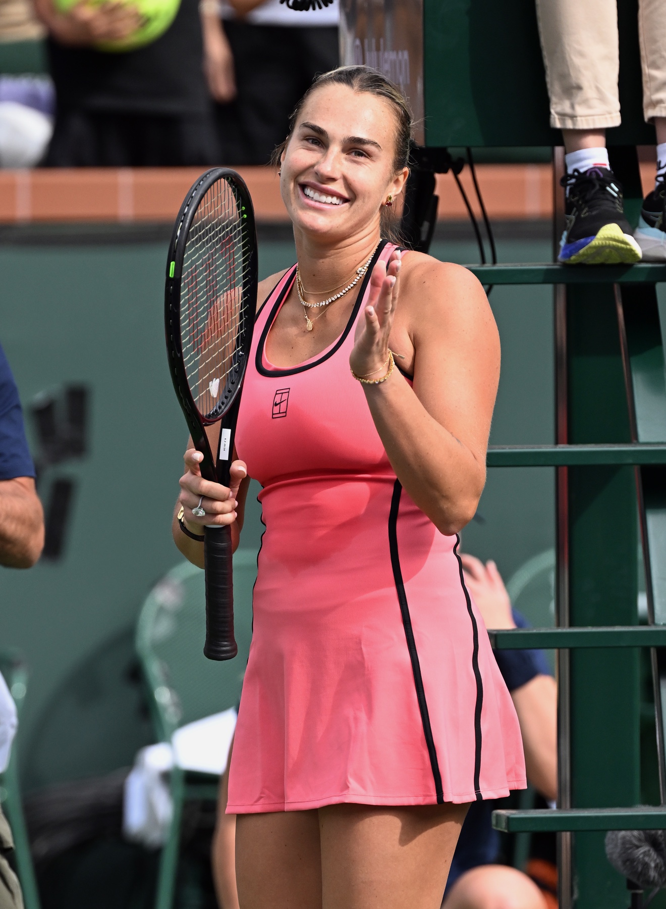 Aryna Sabalenka smiling and waving with her racquet